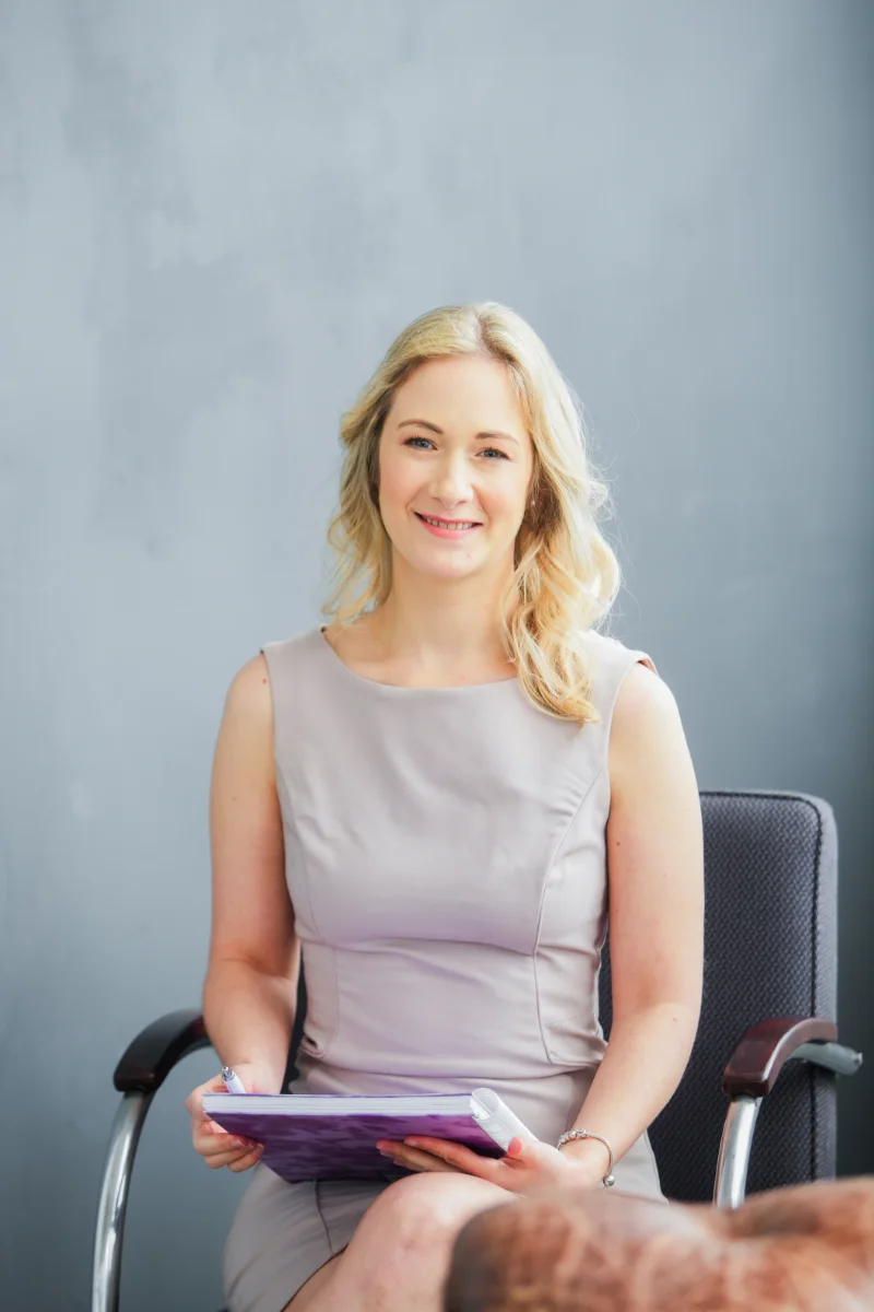 Kateřina Machek v business šatech sedí na židli při pracovním pohovoru